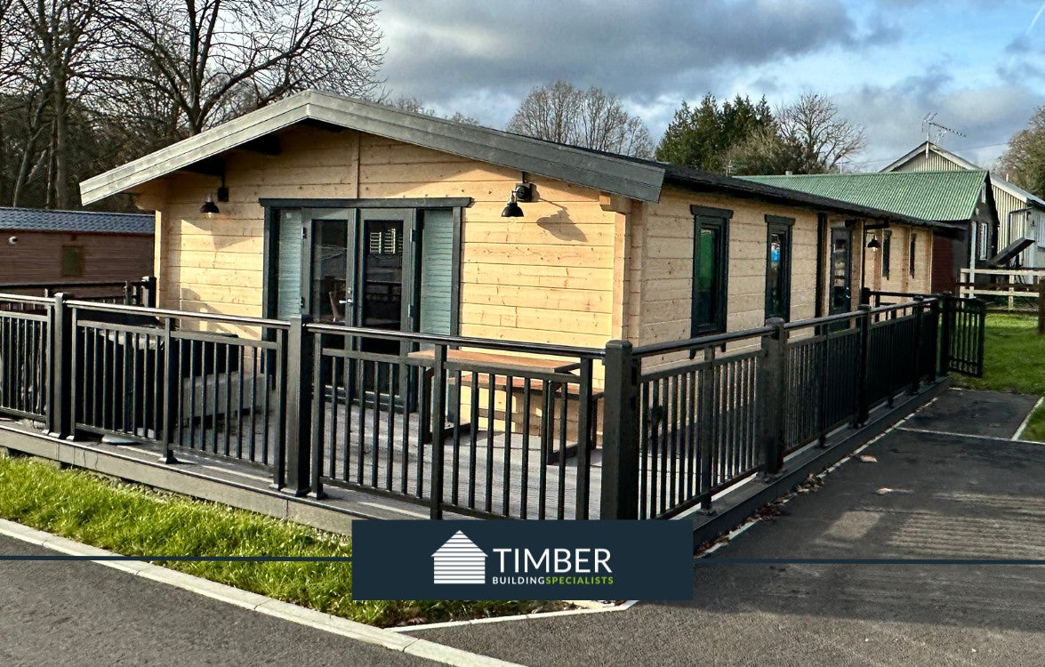 Modern log cabin lodge with timber exterior and fenced veranda in a landscaped setting