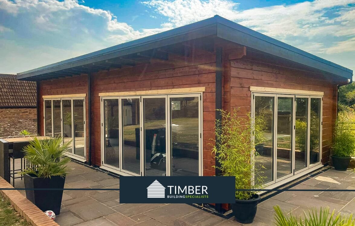 Modern log cabin with large glass doors, timber exterior, and landscaped patio.