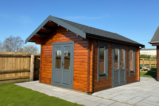 Wide-angle interior view of a garden log cabin Manchester showing double doors, oak walls, and oiled floorboards, Wooden cabin with gray doors and windows on a clear day