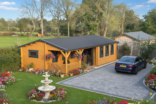 Wooden cabin with a black roof in a garden setting with a fountain and chairs.