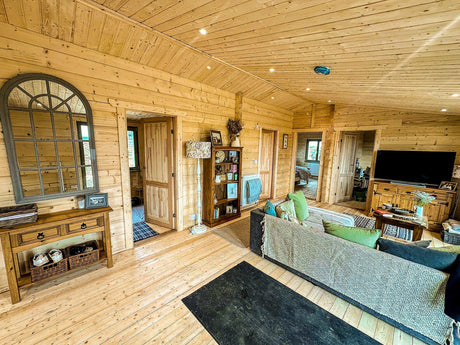 Spacious log cabin interior with wooden walls, open living area, and modern furnishings