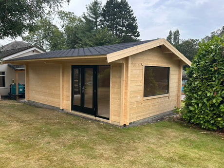 Large log cabin games room with timber cladding, black double doors, and garden setting