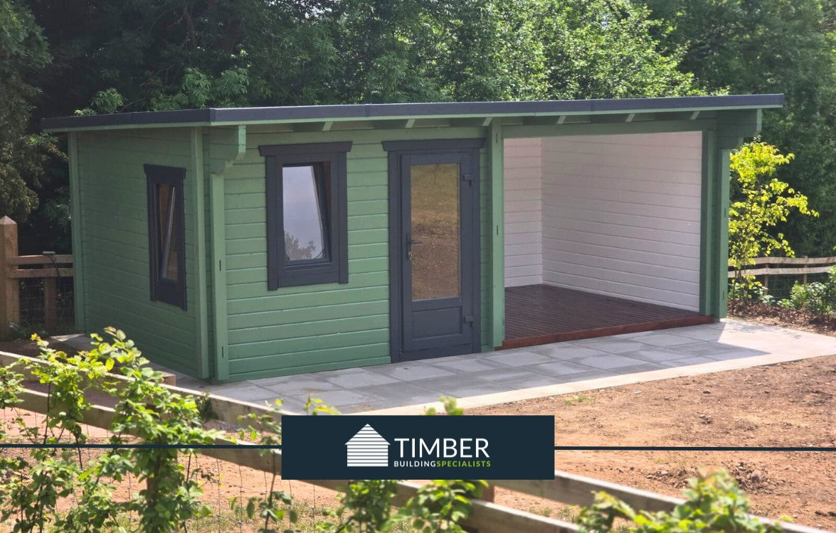 Modern green log cabin with large covered patio and timber construction, set outdoors