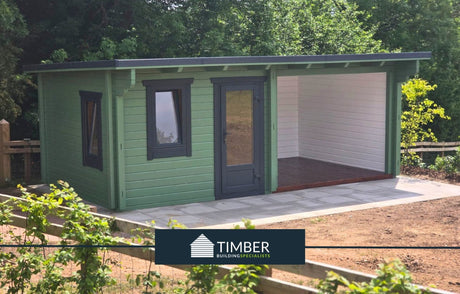 Modern green log cabin with large covered patio and timber construction, set outdoors