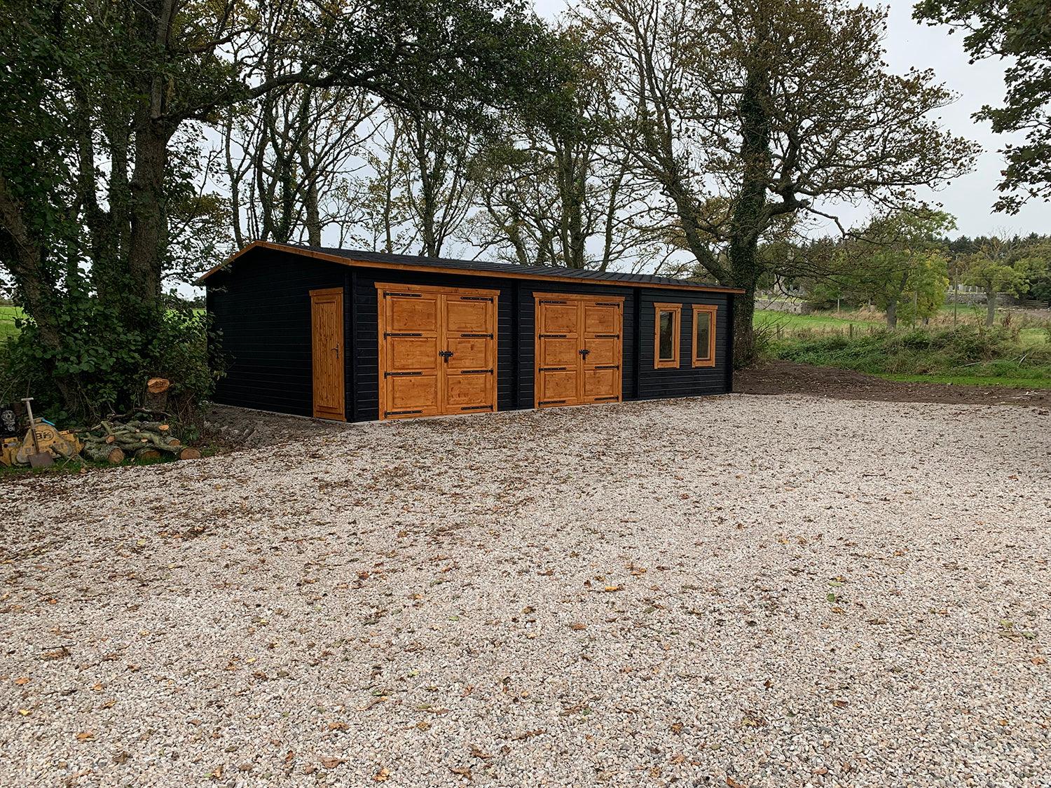 Modern timber double garage with office, wood doors and windows, set in a rural area.