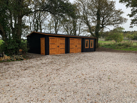 Modern timber double garage with office, wood doors and windows, set in a rural area.