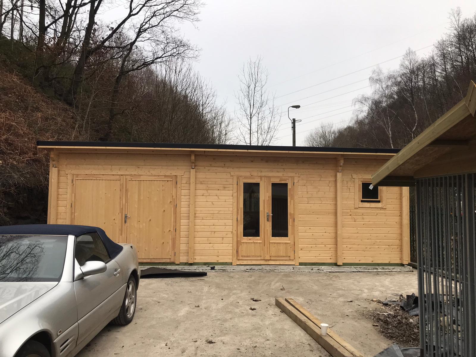 Timber workshop building with double doors, windows, and light wood exterior in a rural setting