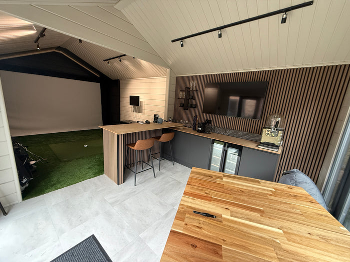 golf sim log cabin internal shot of a bar and golf simulator set up with projector, golf clubs and golf balls